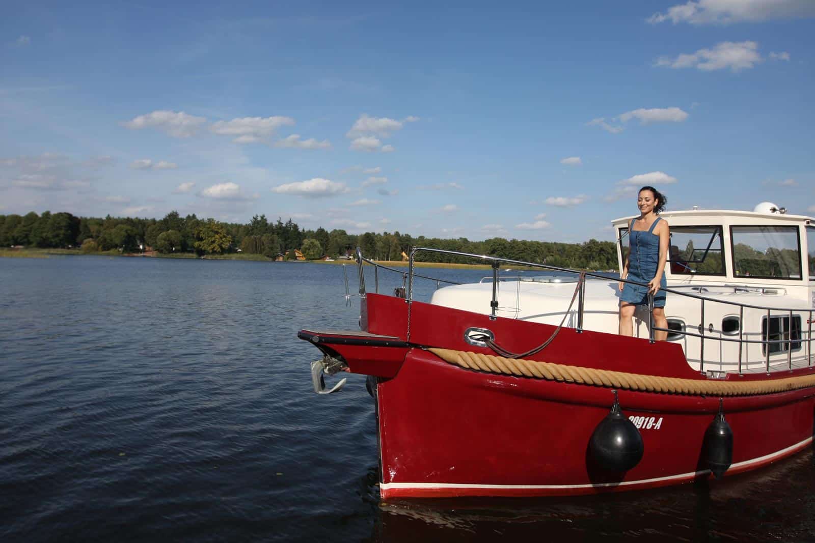 Junge Frau an Bord eines gemieteten Hausbootes auf dem Röblinsee in Fürstenberg an Bord eines River Boats