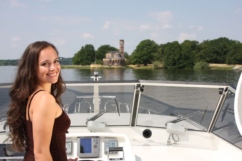 Frau an Bord einer Motoryacht auf der Havel vor der Sacrower Heilandskirche